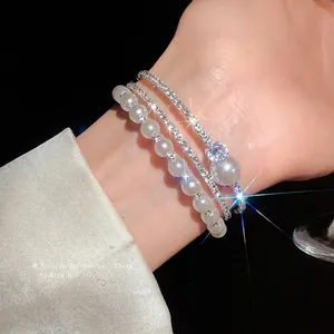 Elegante bracciale rigido multistrato con perle e strass indossato al polso donna