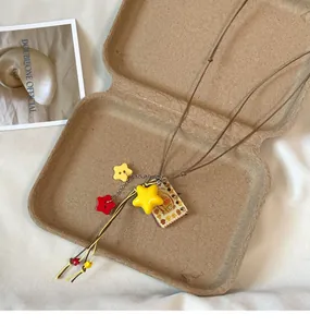 Detailed macro view of the yellow star pendant and vintage book charm on the dopamine style necklace