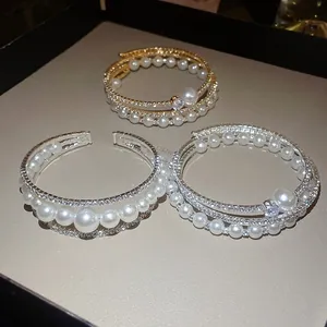 Vista dettagliata di bracciali a strati con strass e perle in oro e argento.