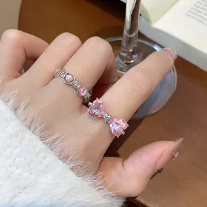 Primo piano di anelli con cristalli rosa a forma di cuore indossati sulle dita