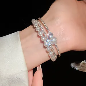 Dettaglio del bracciale aperto multistrato con strass e perle sul polso per un look elegante