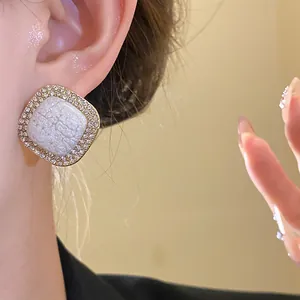 Detailed close-up view of elegant square stud earrings with crystal halo on an ear