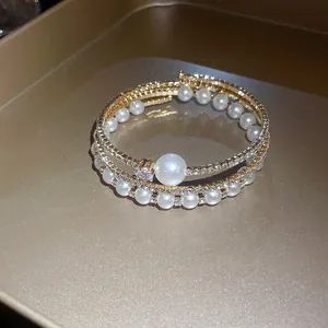 Primo piano di un elegante bracciale multistrato dorato con perle e strass luccicanti