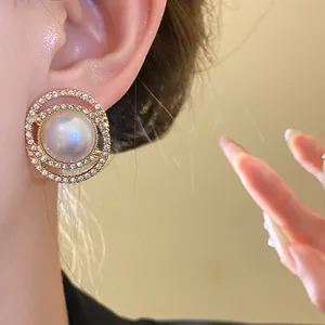 Detailed close-up of elegant gold-toned stud earring with large pearl and rhinestone halo