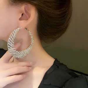 Primer plano exquisito de aros de luna brillantes con pedrería pavé en la modelo