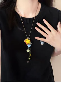 Close-up detail of a colorful dopamine star pendant necklace worn on a black knitted vest
