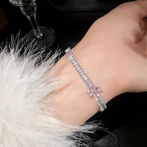 Detailaufnahme eines eleganten Zirkon-Armbands mit rosa Blumenanhängern am Handgelenk