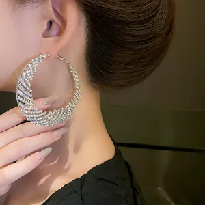 Primer plano detallado de aretes de aro grandes en forma de media luna con pedrería fina