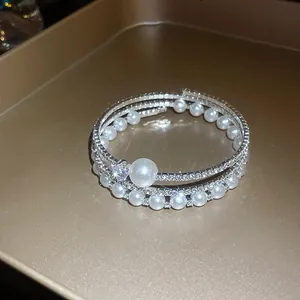 Dettaglio ravvicinato che mostra perle e strass del bracciale multistrato elegante
