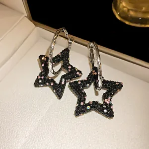 Primo piano di eleganti orecchini a forma di stella nera con strass rosa e cerchi argentati
