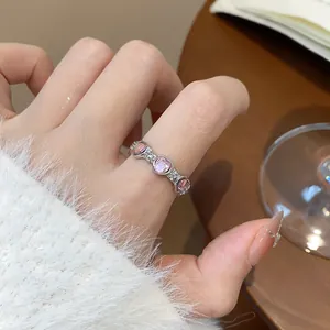 Elegante vista macro di un anello a cuore in argento con pietre rosa su una mano.