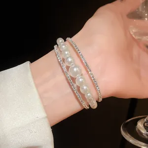 Primo piano di un elegante bracciale a più strati con perle e strass da donna.