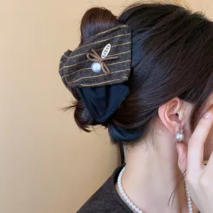 Détail d'une pince à cheveux en tissu rayé marron avec perle et petit nœud décoratif