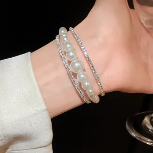 Elegante bracciale a più strati con perle lucenti e strass scintillanti indossato al polso