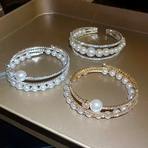 Dettaglio di eleganti bracciali a più strati con perle e cristalli su vassoio dorato