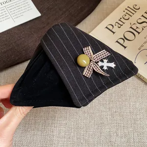 Vue détaillée de la pince à cheveux en tissu rayé noir avec nœud et breloque en croix
