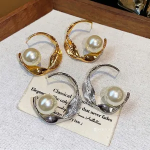 Elegantes pendientes de aro de metal retorcido con perlas en oro y plata de estilo minimalista.