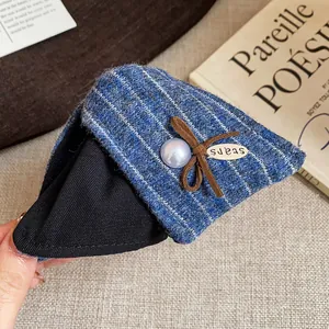 Détail d'une pince à cheveux triangulaire en tweed rayé bleu avec nœud et perle