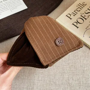 Gros plan de la pince à cheveux en tissu rayé marron avec doublure en velours et bouton