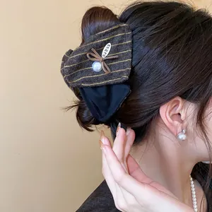 Gros plan d'une pince à cheveux avec nœud en tissu et perle sur cheveux sombres