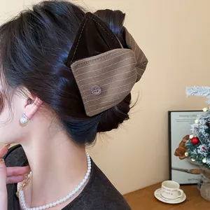 Vue détaillée d'une grande pince à cheveux en tissu marron avec un nœud élégant