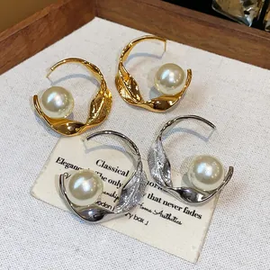 Detalle de pendientes de aro retorcidos con perlas grandes en oro y plata