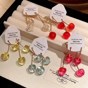 Detailed close-up of colorful cherry-shaped resin earrings on jewelry display tags