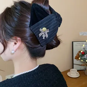 Gros plan détaillé d'une élégante grande pince à cheveux noeud noir rayé sur un chignon.