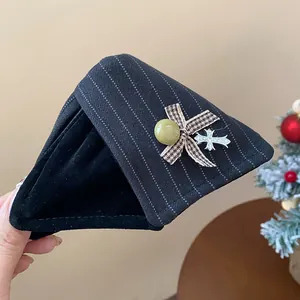 Détail d'une pince à cheveux en tissu avec rayures, nœud papillon et breloque croix