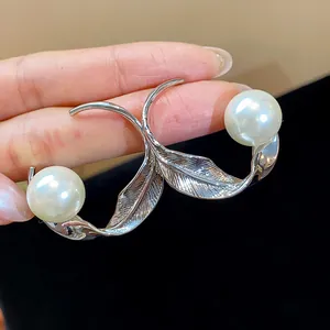 Primer plano de pendientes de hoja plateada con perlas y textura metálica elegante