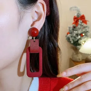 Festive red rectangular drop earrings with silver needle shown on an Asian model