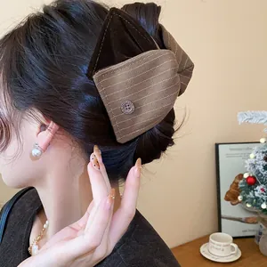 Gros plan détaillé d'une pince à cheveux à nœud rayé marron sur le mannequin
