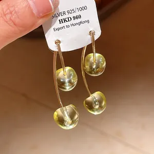 Close-up of translucent yellow cherry resin earrings with gold stems and 925 silver needle.