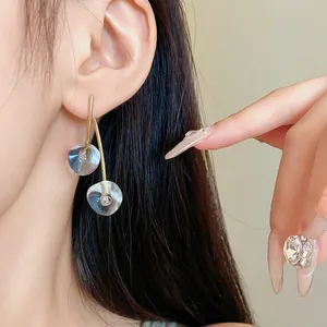 Close-up of minimalist clear resin cherry drop earrings with gold-tone stems on ear
