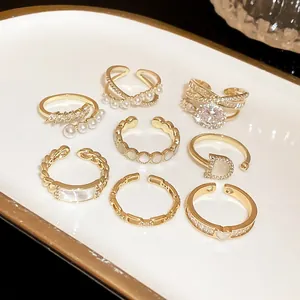 Detailed view of various gold-toned adjustable rings with pearls and cubic zirconia stones