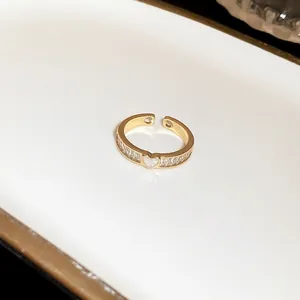 Macro detail of a gold-toned open ring featuring heart and baguette-cut cubic zirconia stones