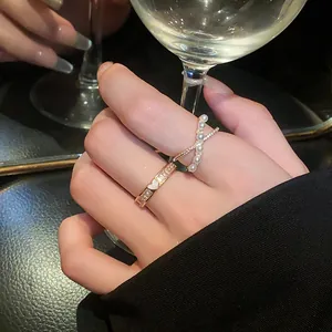 Close-up detail showing an elegant gold zircon ring paired with a pearl cross ring on finger