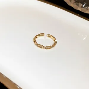 Close-up detail of an elegant gold oval link open ring with sparkling cubic zircon inlays
