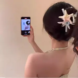 Close-up of an elegant starfish and flower hair claw clip worn on a model's dark hair