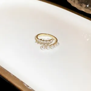 Detailed view of an elegant gold open ring featuring oval cubic zirconia and white pearls.