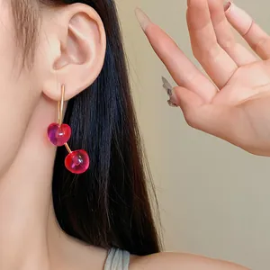 Close-up of translucent red resin cherry earrings on model, minimalist Korean style.