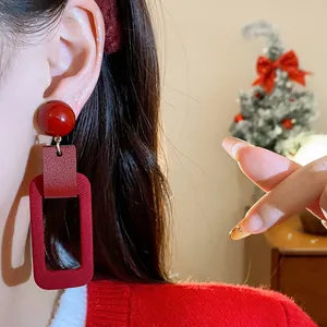 Detailed view of red rectangular drop earrings with silver needles for festive occasions