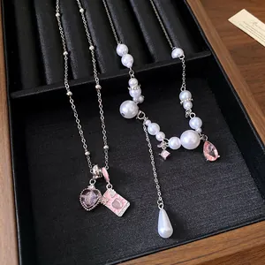 Close-up of a silver pearl necklace with pink heart and envelope pendants in a black tray