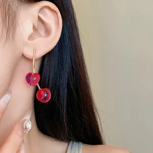 Detailed view of stylish translucent red cherry resin earrings worn by a model