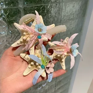 Close-up of elegant acrylic starfish hair claws with fabric flowers and sparkling rhinestones