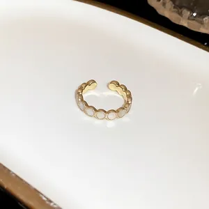 Detailed view of an elegant gold open ring featuring white shell-like circular inlays.