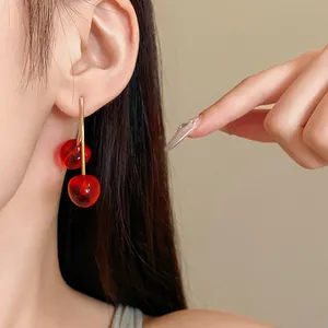 Detailed view of minimalist red cherry resin drop earrings with gold finish needles