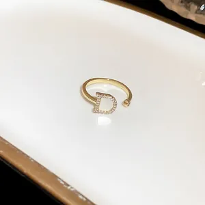 Close-up of gold open ring featuring a pavé zircon letter D charm