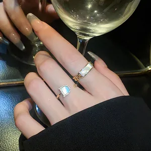 Close-up of elegant gold open rings with zircon and 'D' logo on a hand model.