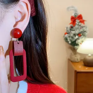 Close-up of red rectangular fabric earrings with vintage texture for a festive New Year look